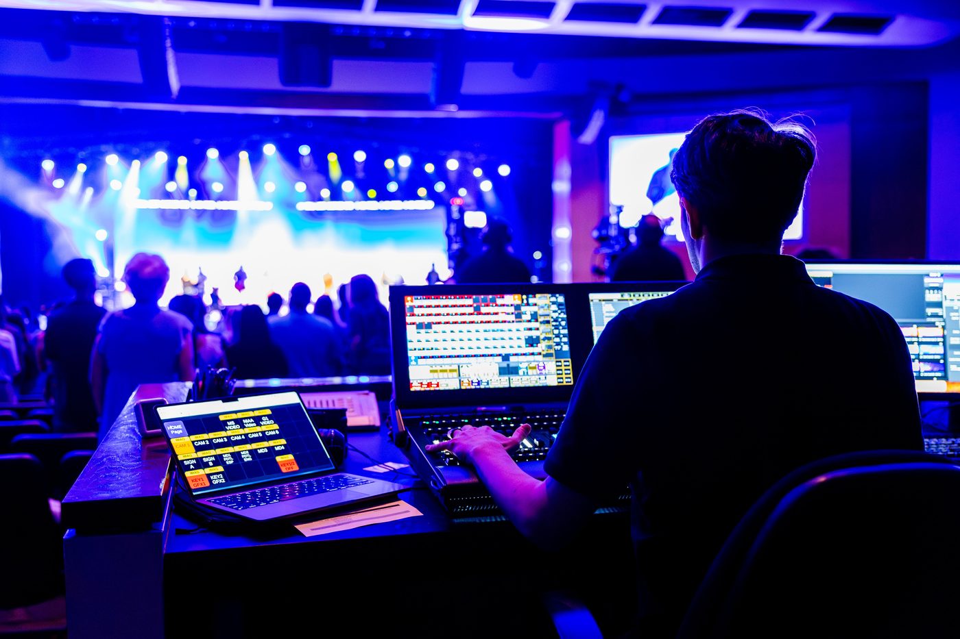 An audio-visual technician at a lighting and sound console during a live event